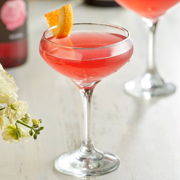 Two glasses of DaVinci rose cocktails with a slice of orange on top.