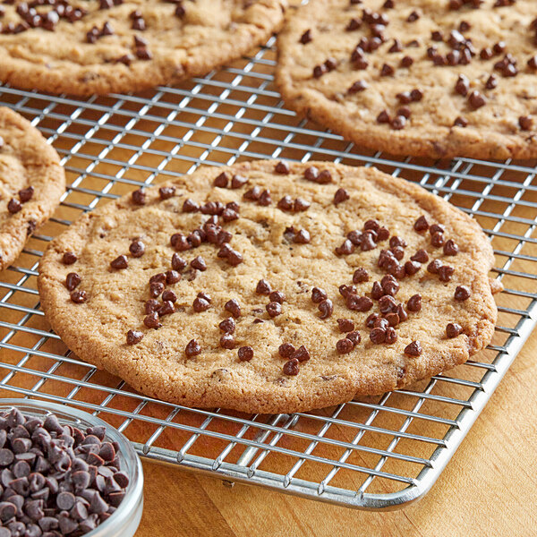 A chocolate chip cookie on a cooling rack with chocolate chips on top.