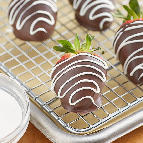 Chocolate covered strawberries on a cooling rack drizzled with Alpine Bright White Vanilla Coating.