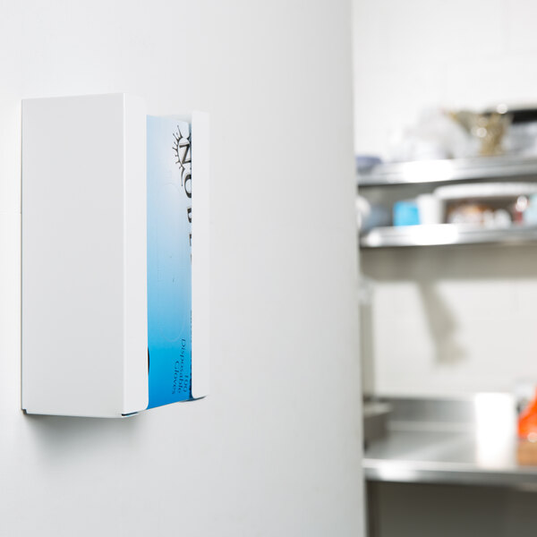 A white rectangular San Jamar disposable glove dispenser with blue and black text on a white wall.