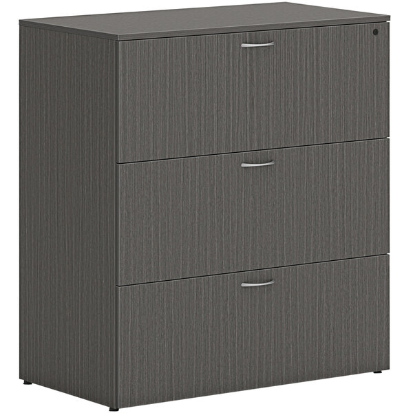 A slate grey HON lateral file cabinet with 3 drawers.