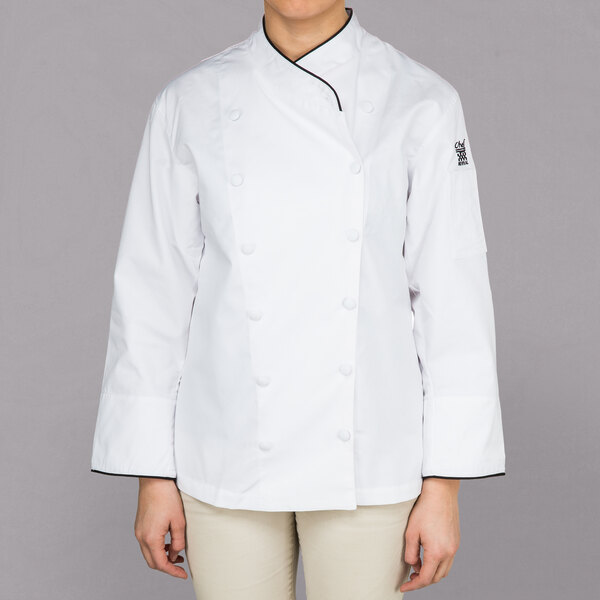 A woman wearing a white Chef Revival long sleeve coat with black piping.