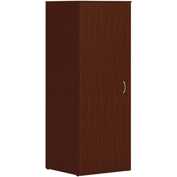 A close-up of a traditional mahogany HON wardrobe cabinet with a door and silver handles.