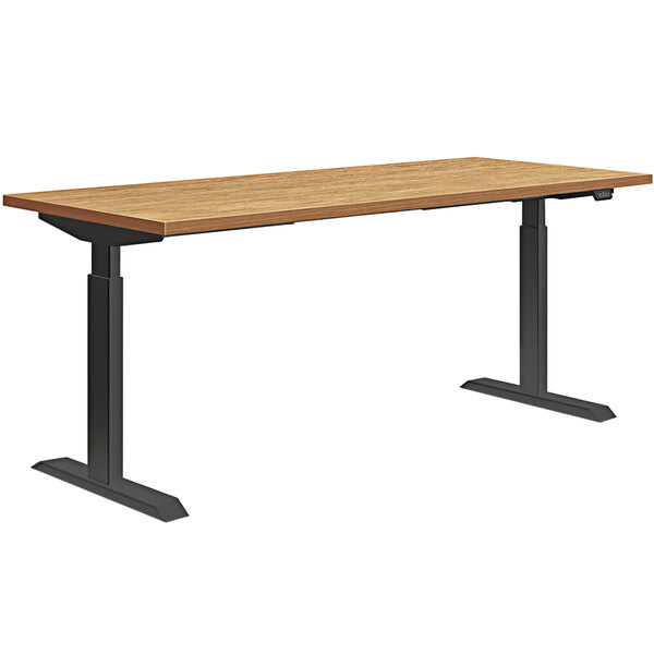 A HON Coze Natural Recon and Black desk top on a table with black legs.