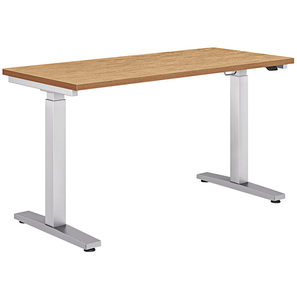 A HON Coze Height-Adjustable Desk with a wooden top and silver metal legs.