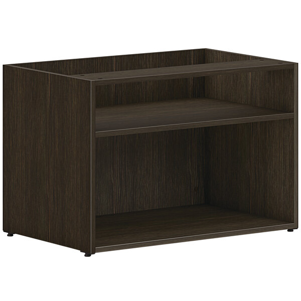 A dark wood HON low open storage credenza with two shelves.