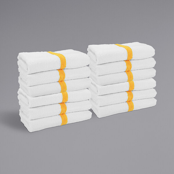 A stack of white towels with gold center stripes.