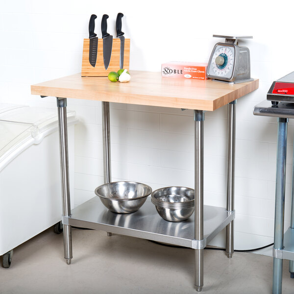 An Advance Tabco wood top work table with a stainless steel base and bowls on it.