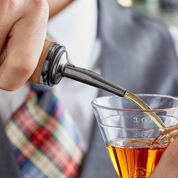 A person using an Acopa black liquor pourer to pour a drink into a glass.