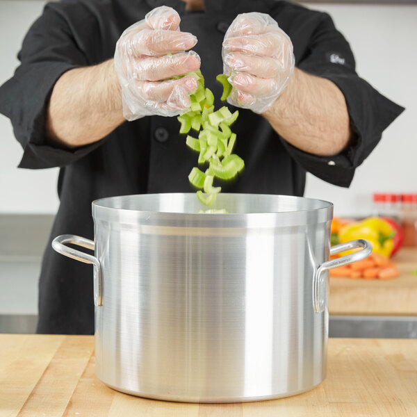 A chef cooking vegetables in a Vollrath classic aluminum stock pot.