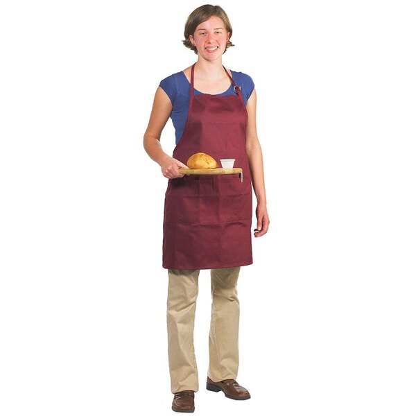 A woman wearing a burgundy Chef Revival apron holding a tray of bread.
