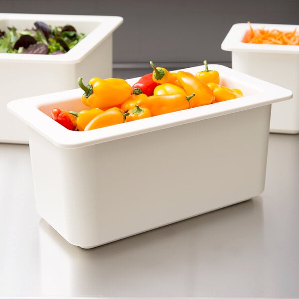 A white Cambro food pan filled with yellow and red peppers.