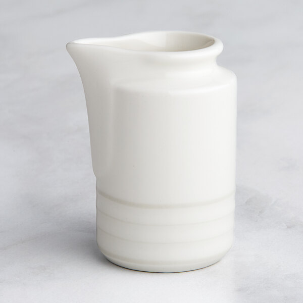 A RAK Porcelain ivory embossed porcelain creamer on a table.