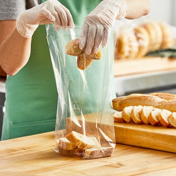 A person in gloves putting bread in a Choice plastic bag.