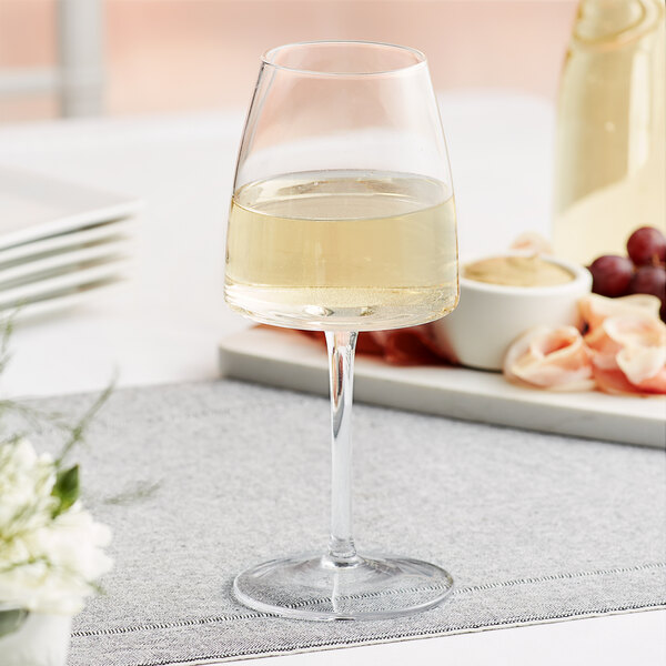 An Acopa white wine glass full of white wine on a table.