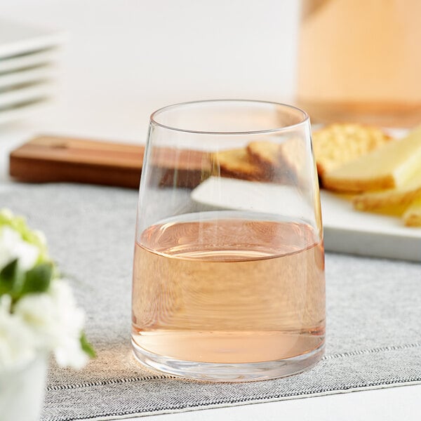 An Acopa stemless wine glass filled with pink liquid on a table.