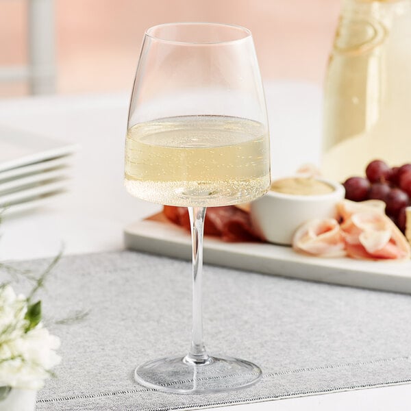 An Acopa Piatta wine glass full of white wine on a table.