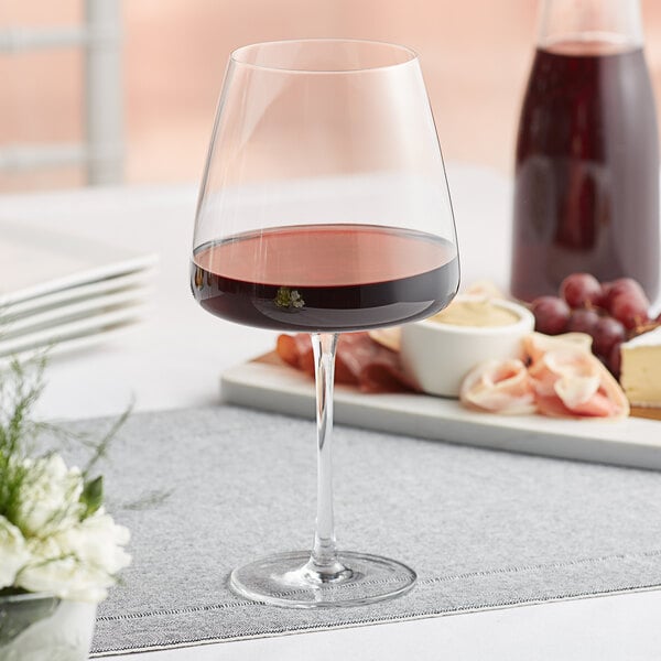 An Acopa red wine glass filled with red wine on a table.