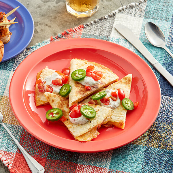 An Acopa orange narrow rim plate with a quesadilla, jalapenos, and tomatoes on a table.
