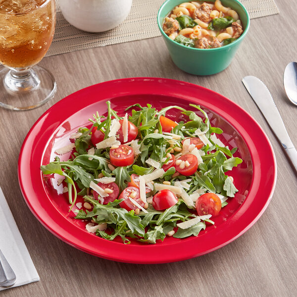 A red Acopa Foundations narrow rim melamine plate with a salad and a drink on a table.