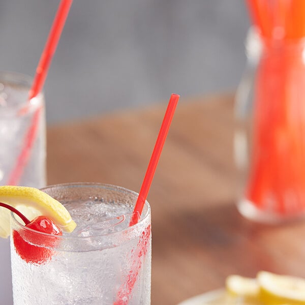 A glass of ice water with a red Choice Collins straw in it.
