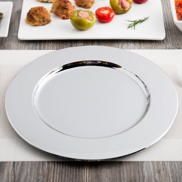 A Carlisle chrome charger plate with food on it.