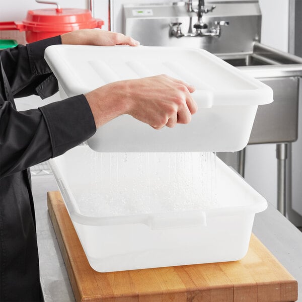 A hand holding a white polypropylene Choice drain box over a sink full of water.