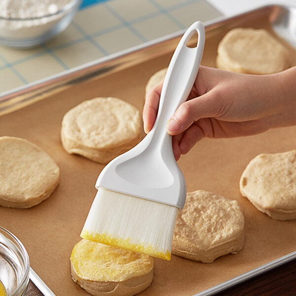 A person using a Royal Industries pastry brush to baste biscuits.