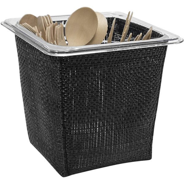 A black woven vinyl deep housing pan set in a black random weave basket with utensils inside.