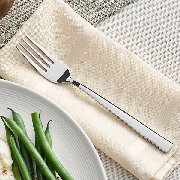 An Acopa stainless steel dinner fork on a white plate with green beans.