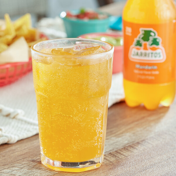 A glass of Jarritos Mandarin Soda on a table in a Mexican restaurant.