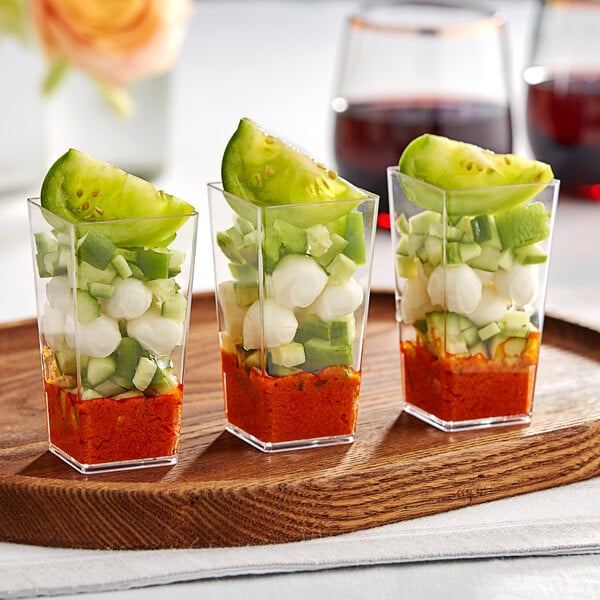 Three Choice clear square plastic mini cups filled with vegetables and cheese.