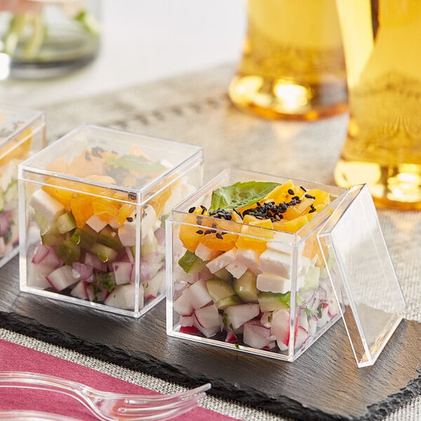 A group of Visions clear plastic mini cubes with food in them on a table.