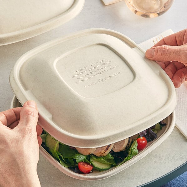 Two people's hands holding a World Centric compostable container of salad.