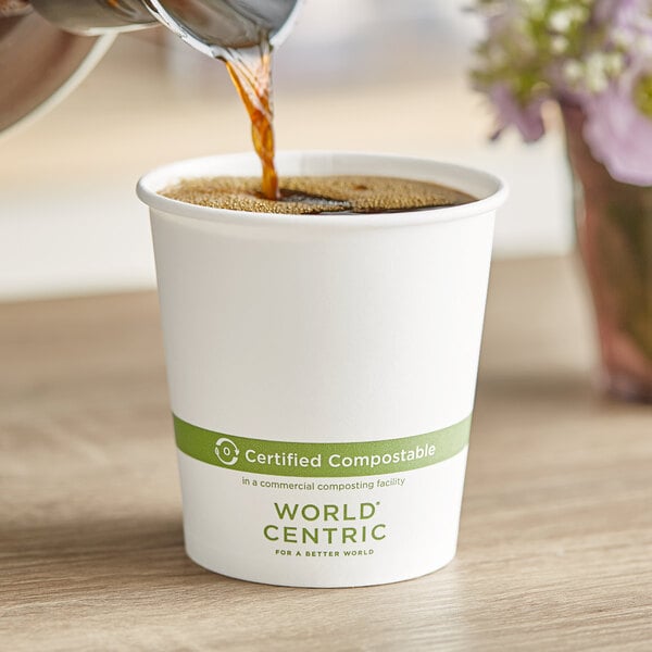A World Centric white compostable paper hot cup filled with brown coffee being poured into.