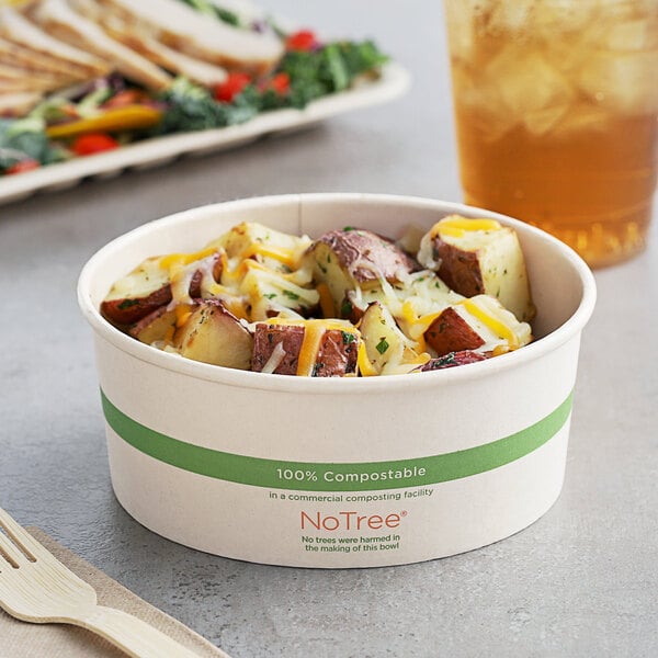 A World Centric compostable paper food cup filled with potatoes and cheese on a table.