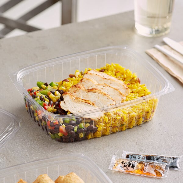 A World Centric compostable rectangular deli container filled with food on a table.
