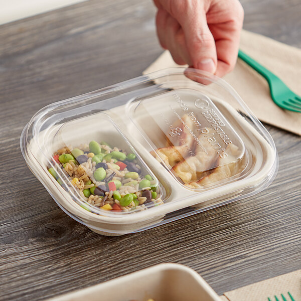 A hand holding a World Centric compostable plastic container with food inside.