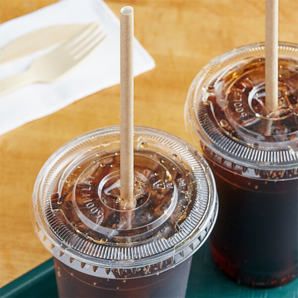 Two plastic cups with brown liquid and World Centric paper straws on a tray on a table.