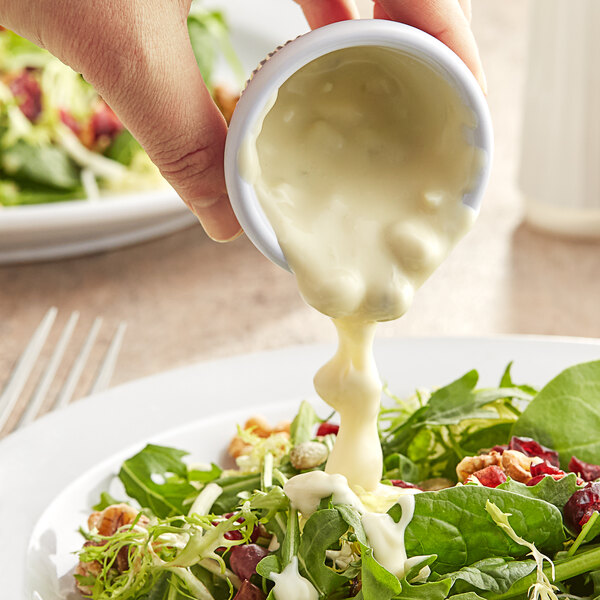 A person pouring Kraft Blue Cheese Dressing onto a salad at a salad bar.