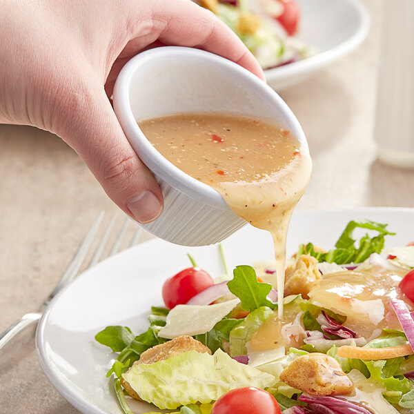 A person pouring Kraft Fat-Free Italian Dressing onto a salad.