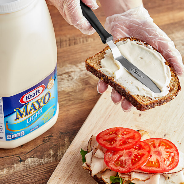 A person spreading Kraft Light Mayonnaise on a sandwich with a knife.