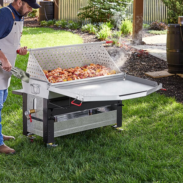 A man using a Backyard Pro Cajun Seafood Boiler Cart to cook food on a table outdoors.