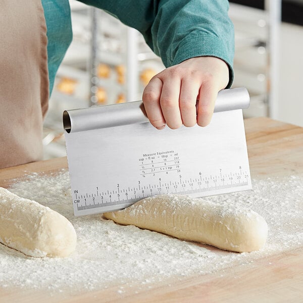 A person using a Choice stainless steel dough cutter to measure dough on a counter.