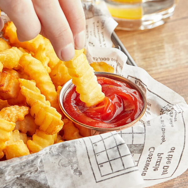A hand dipping a french fry into a container of Heinz Simply Ketchup.