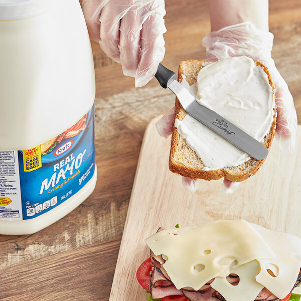A person spreading Kraft Real Mayonnaise on a sandwich.