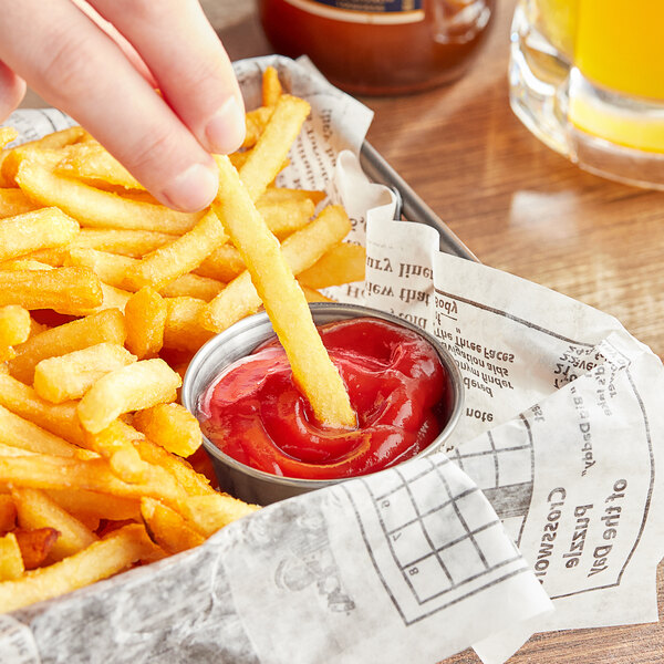 A person holding a french fry and dipping it into a container of Heinz Organic Ketchup.