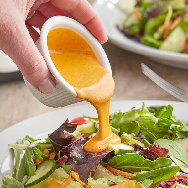 A person pouring Kraft Creamy French Dressing onto a salad at a salad bar.