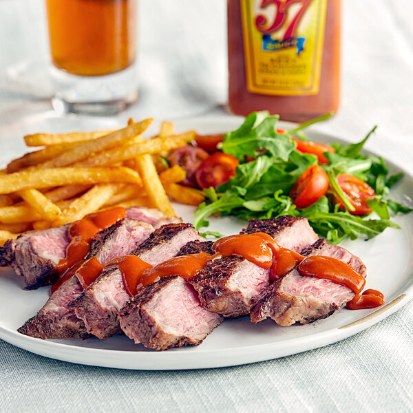 A plate of steak and fries with a bottle of Heinz 57 Sauce on the side.