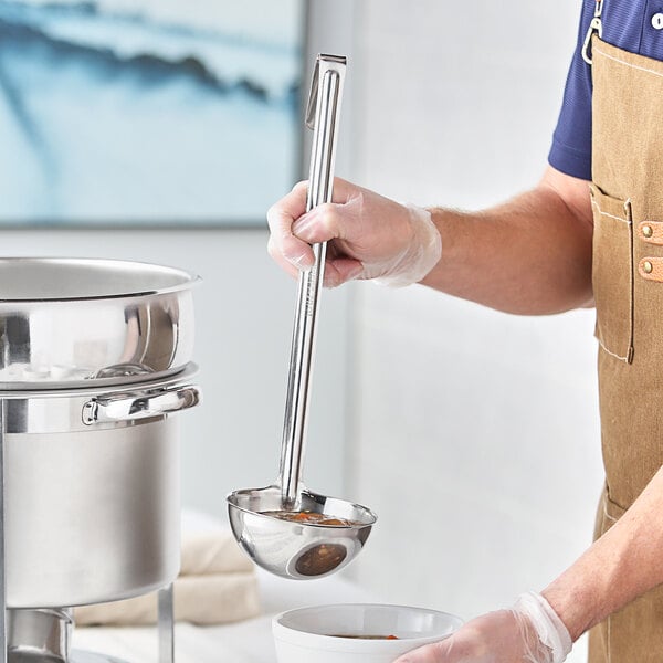 A person using a Choice stainless steel ladle to pour food into a bowl.